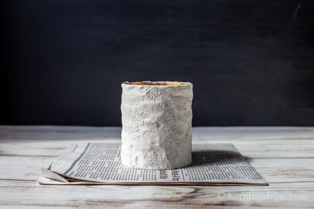 Aluminum can with a thick coating of Plaster of Paris on newspaper.