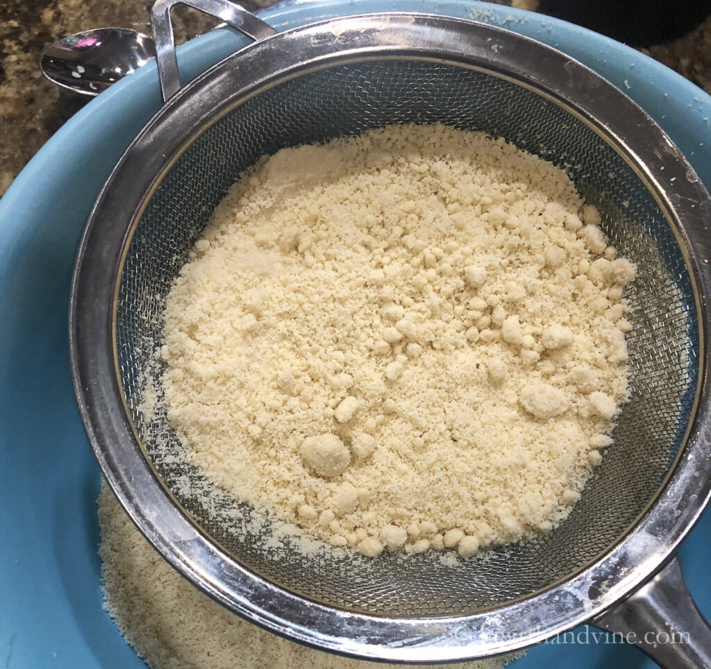Sifting almond flour into a bowl.