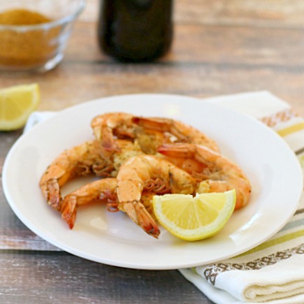 Steamed shrimp on a plate with a lemon wedge.