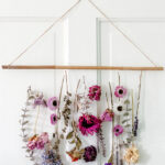 Dried flowers hanging from a dowel rod on a white door.