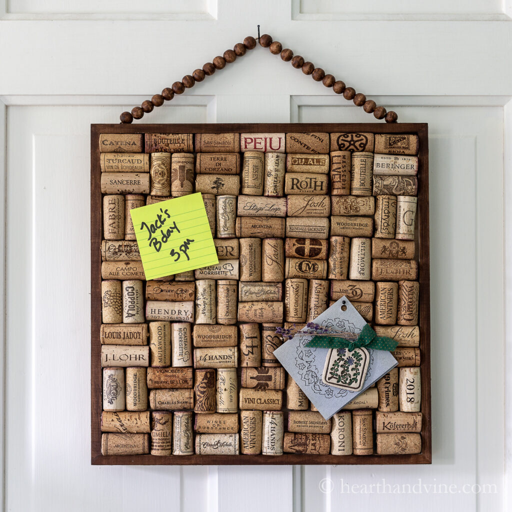 Square frame with beaded hanging stain and filled with recycled wine corks to make a cork board.