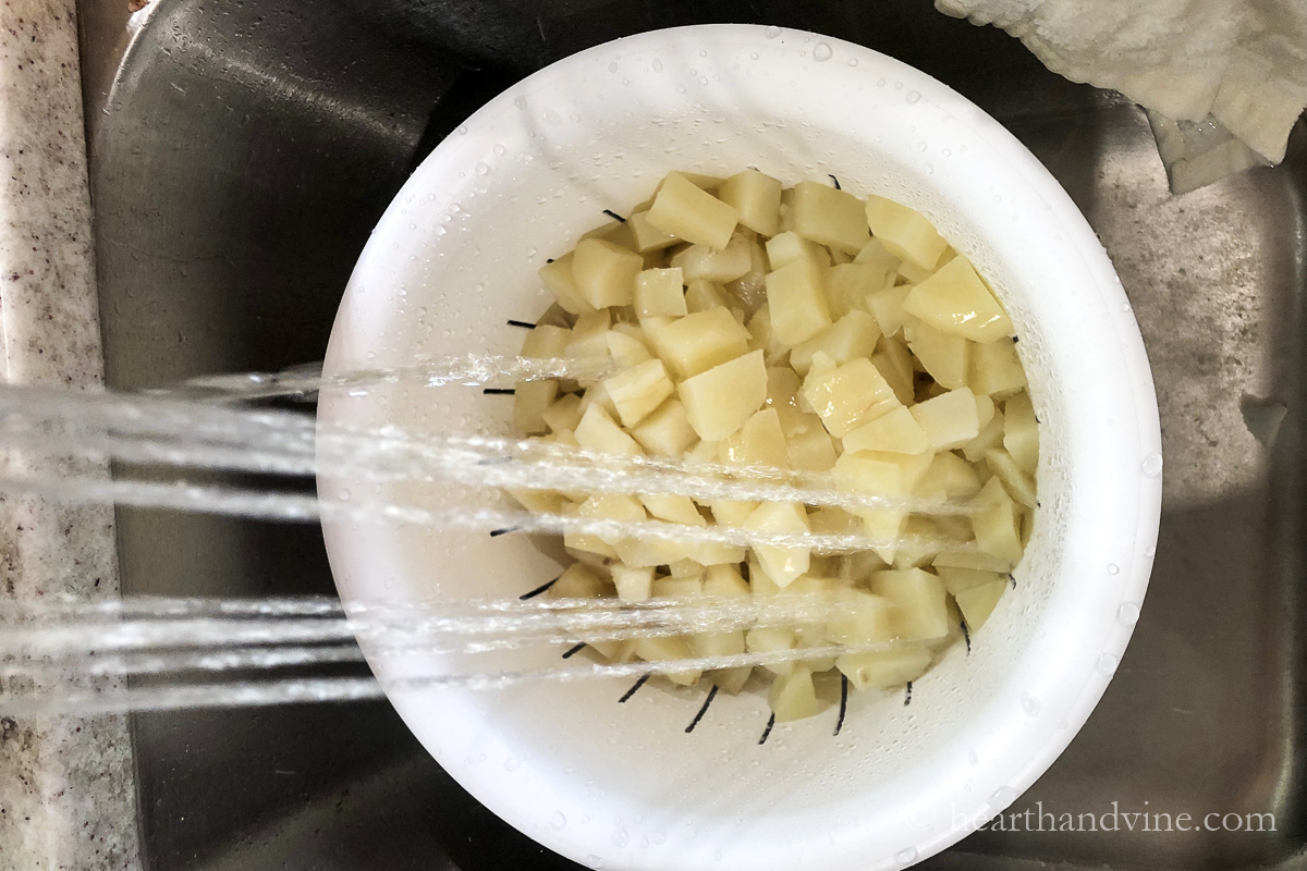 Diced boiled potatoes rinsed in the sink.