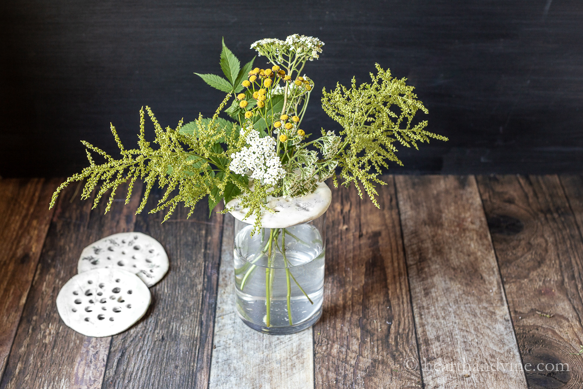 DIY flower frogs made from clay. Two on the side and one on top of a vase with flowers.