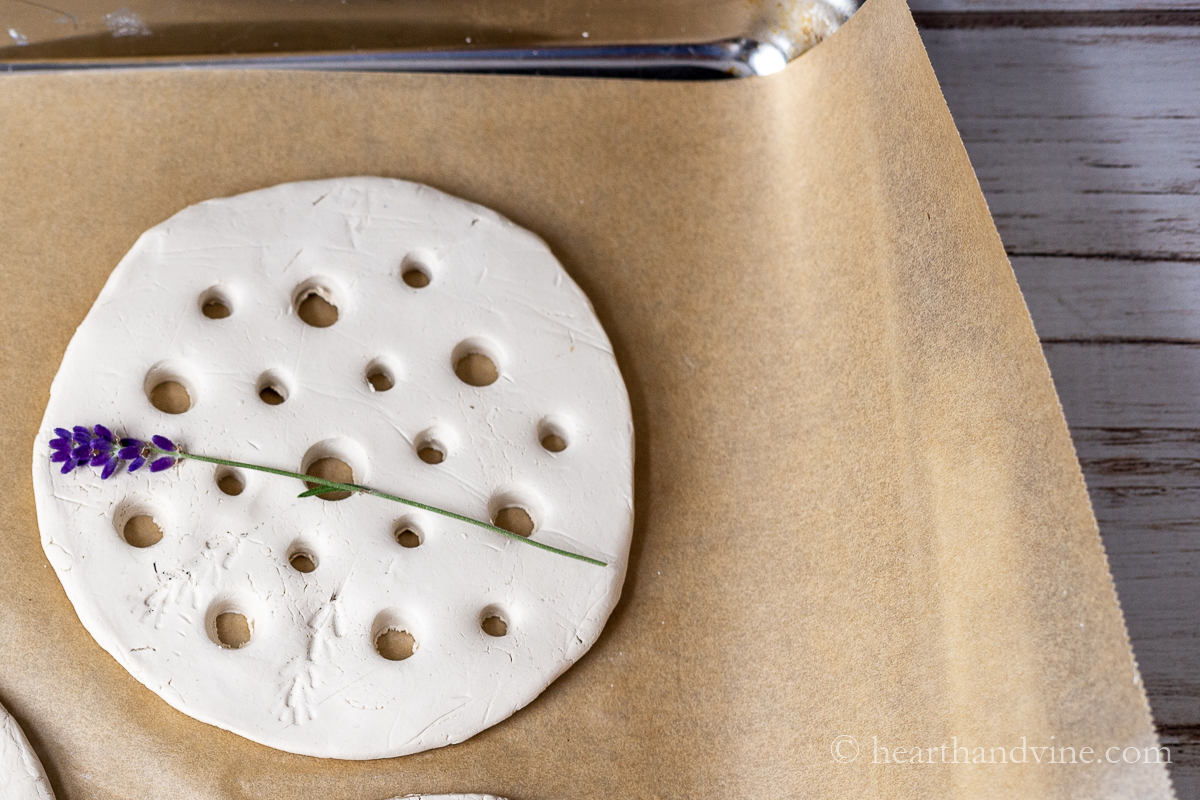 Pressing a lavender flower and stem into a air dry clay flower frog.