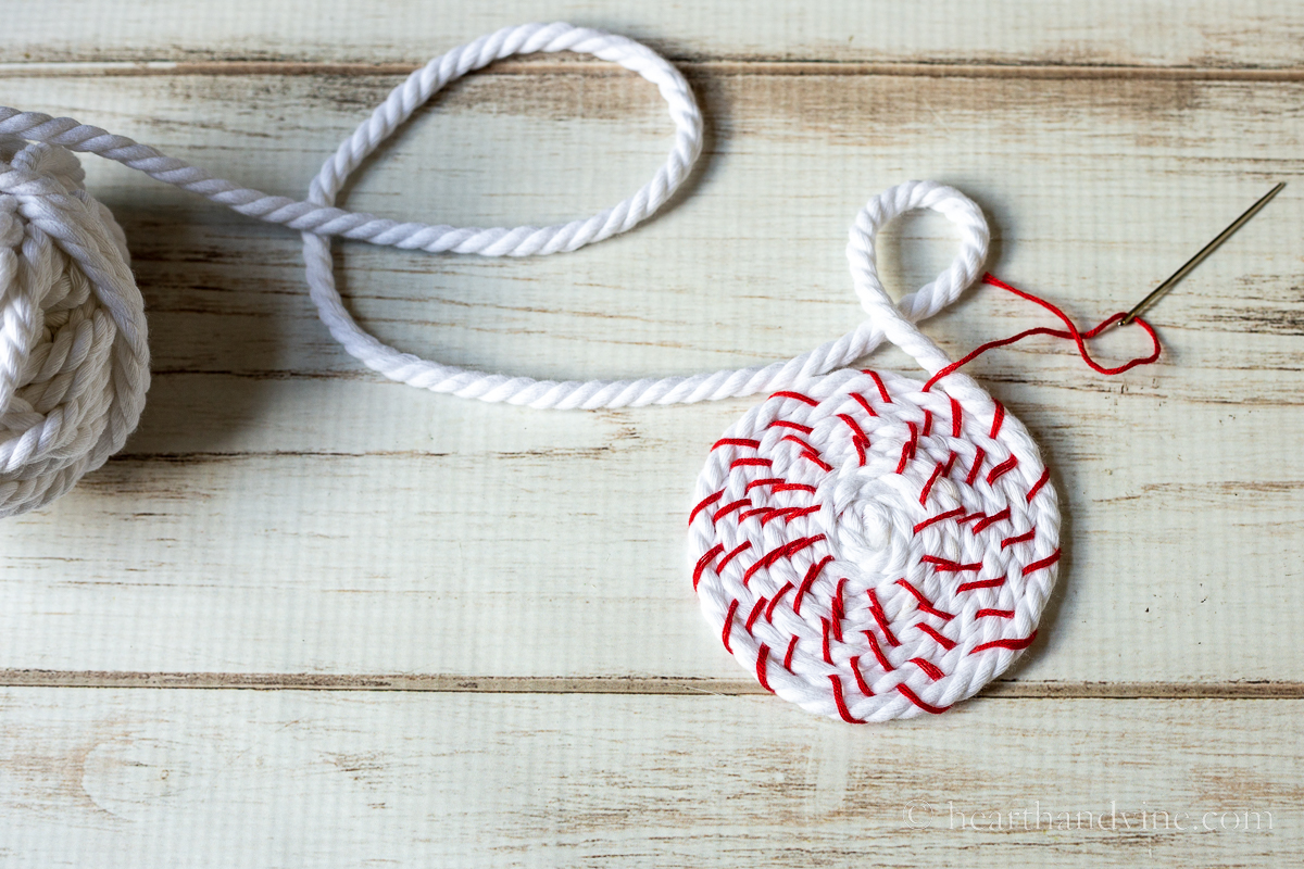 Small coil of white rope stitched together with red embroidery thread and a large needle.