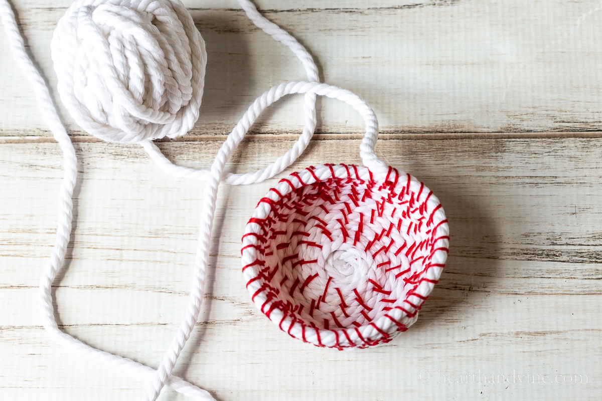 Ball of white rope/cording and a red stitched coil basket at the end.