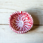 Small coiled rope basket in red and white.