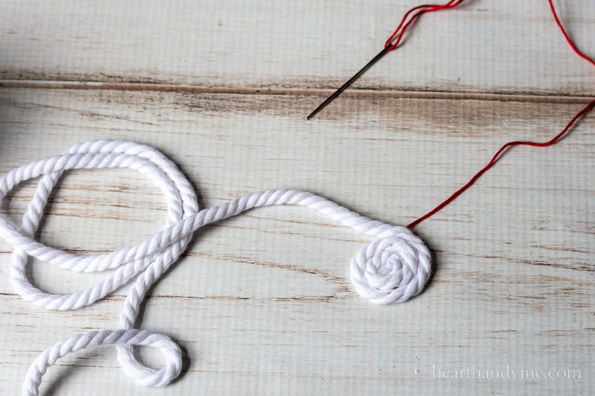 Tiny coil of white rope stitched together with red thread.