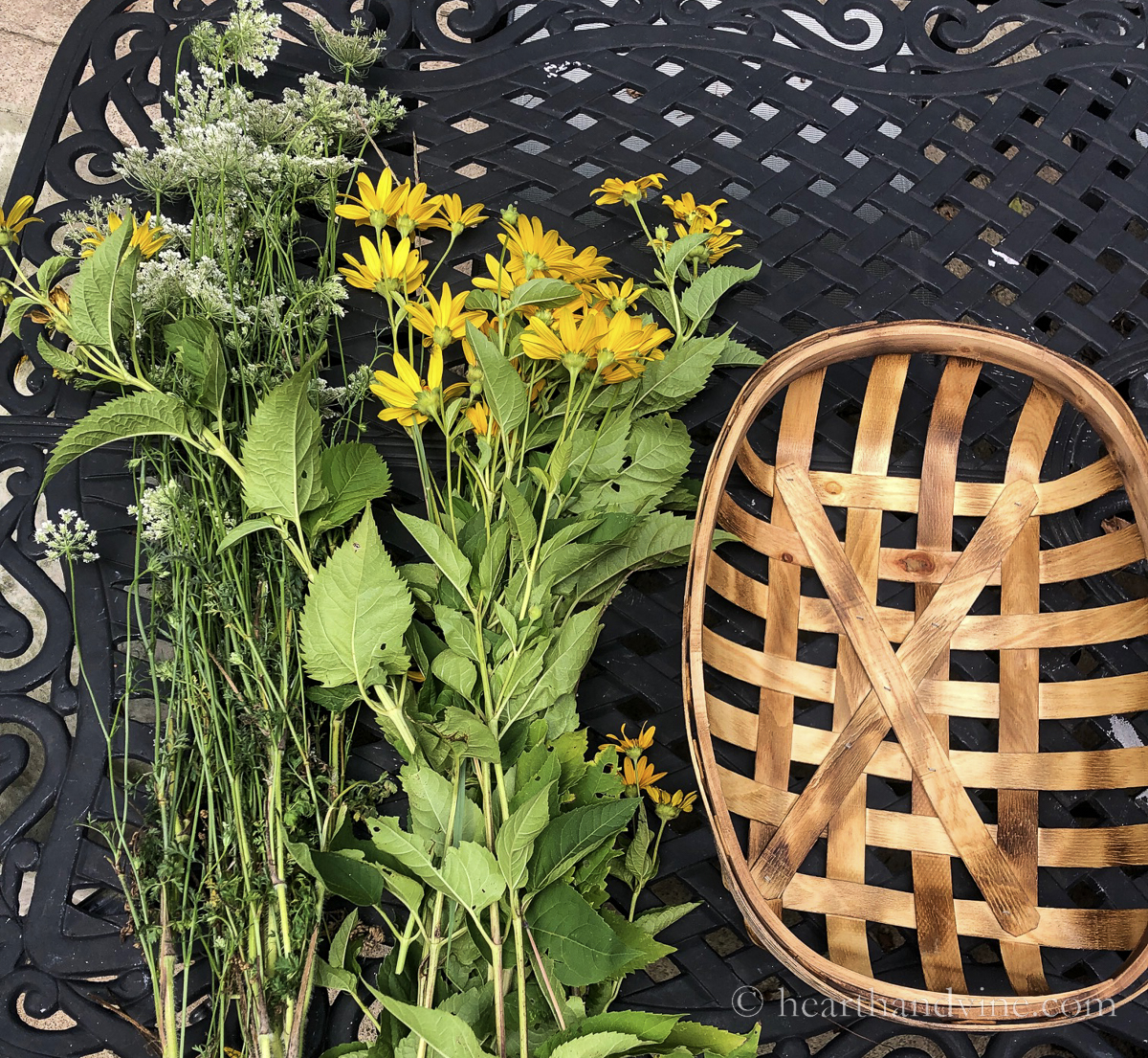 Tobacco basket next to wild sunflowers and queen anne's lace flowers on a table.