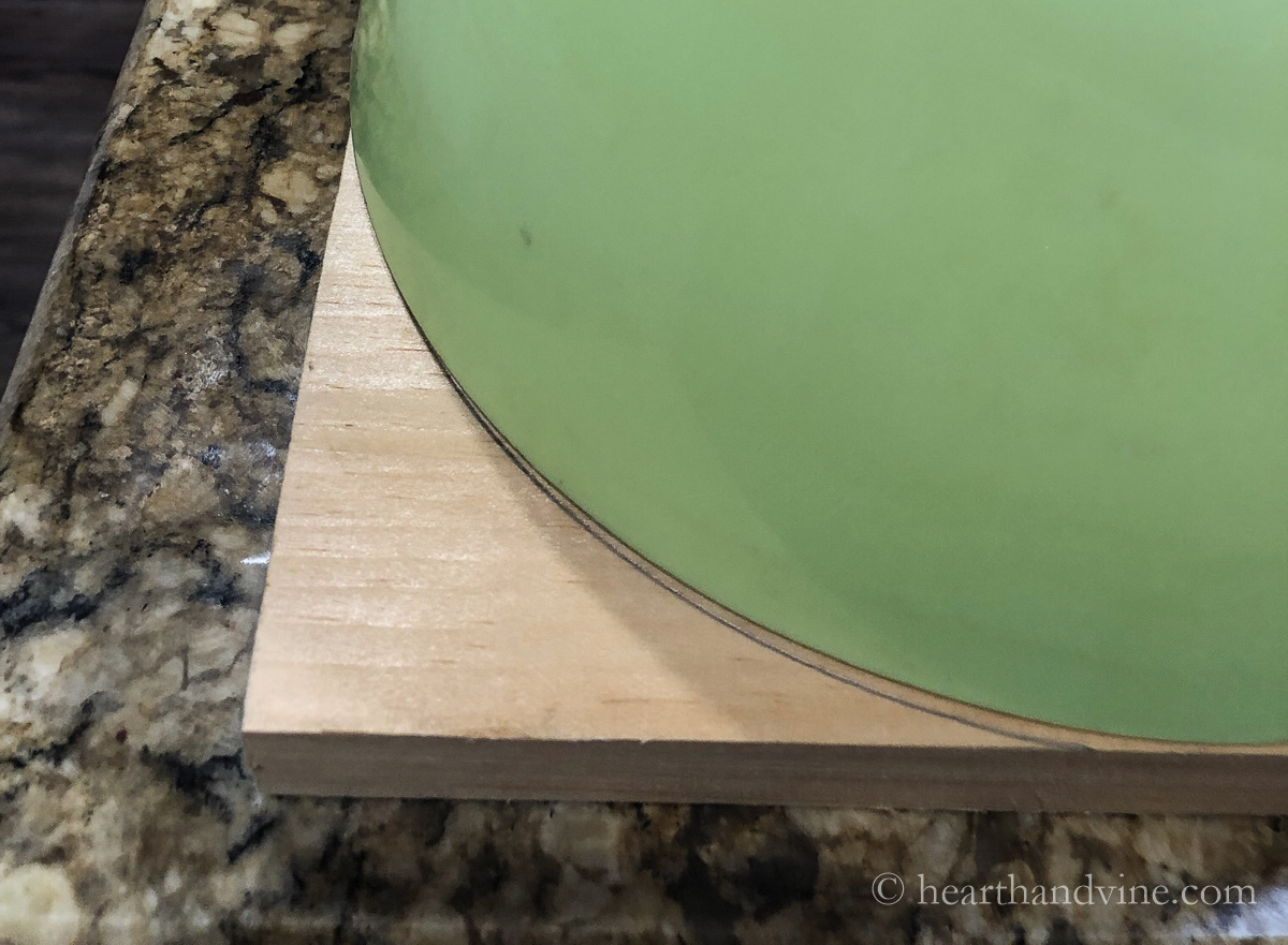 Plastic bowl edge used to trace a rounded edge on a piece of pine wood.