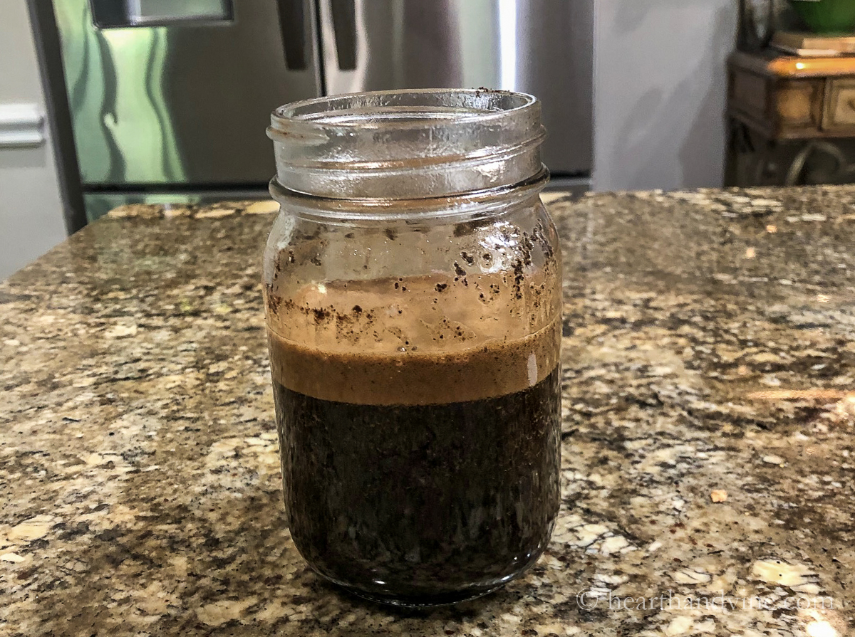 Mason jar filled half with coffee grounds and half with boiling water.