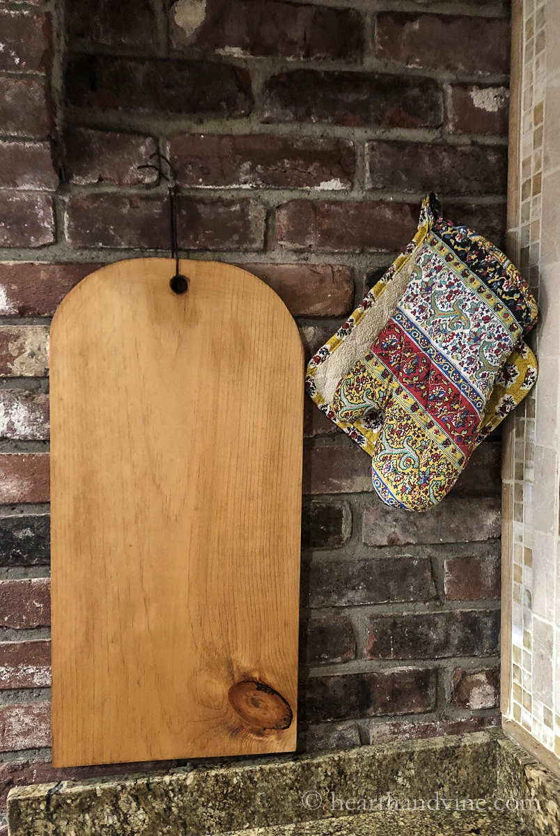 DIY charcuterie board hung on a brick wall.