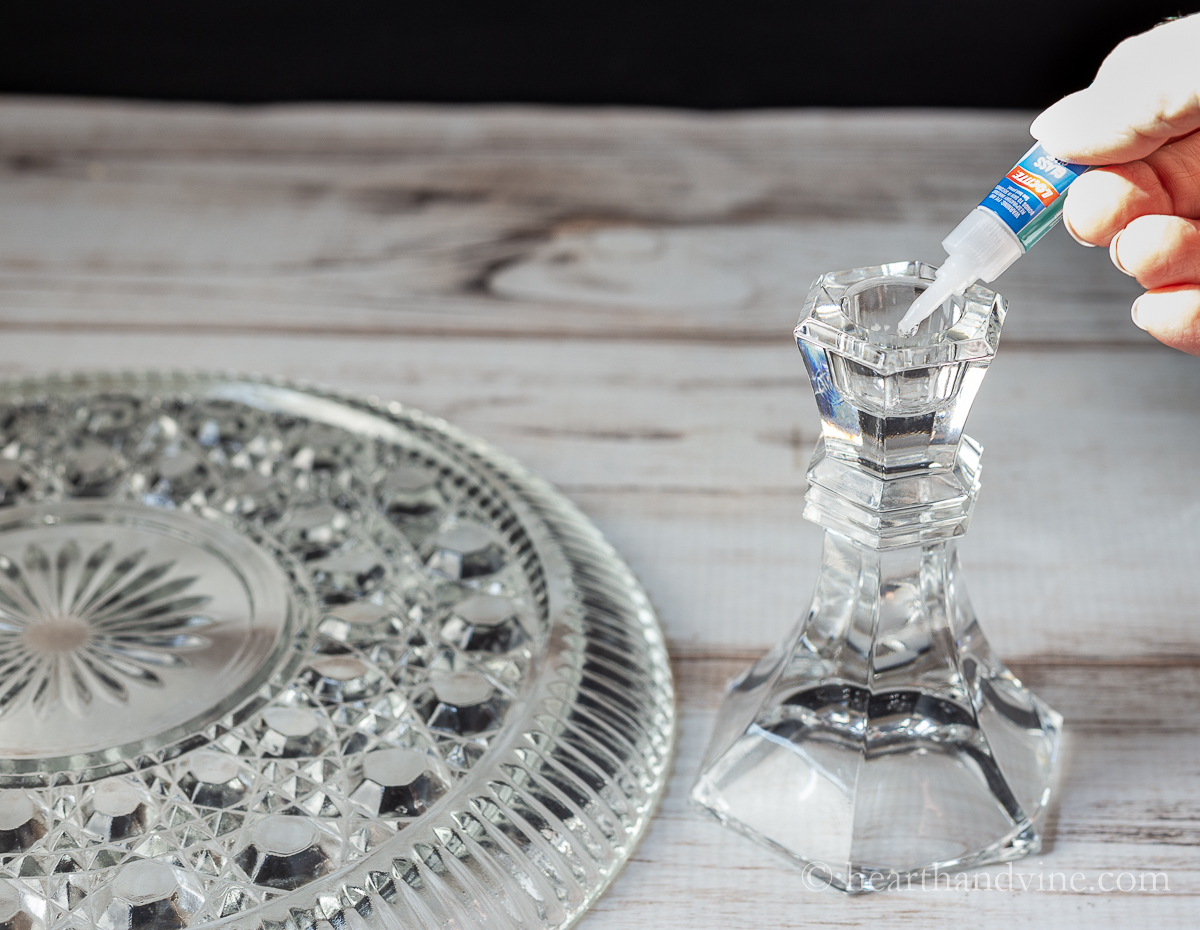 Glass glue being applied to the top of a clear glass candlestick.