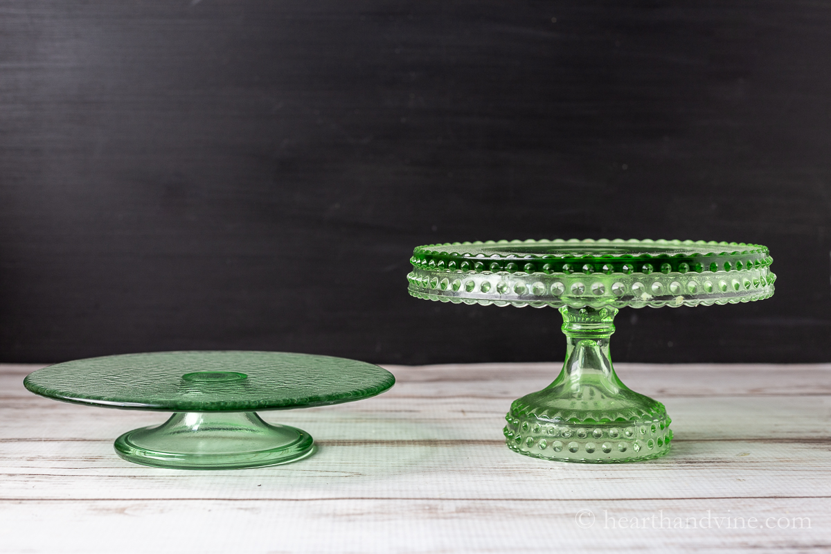 Two green glass cake stands at different heights.