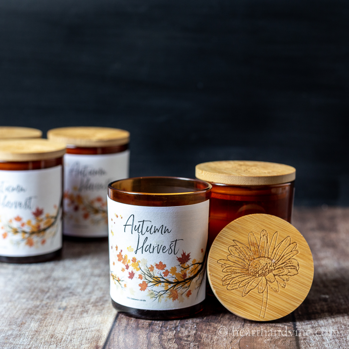 Amber glass jar diy beeswax candles with Autumn Harvest label and wooden lid with flower etching.