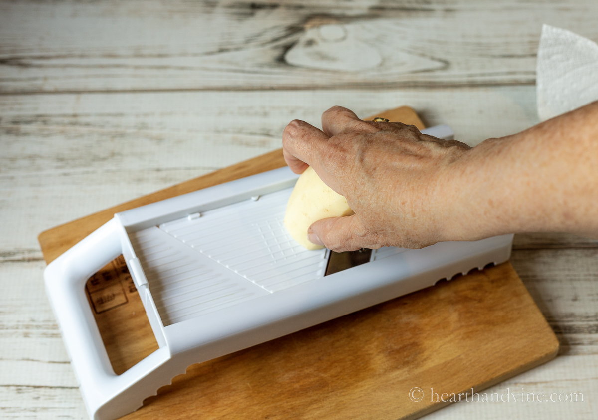 Using a mandoline to slice potatoes.