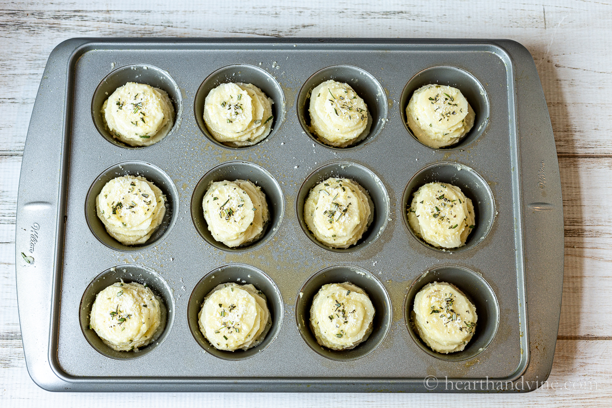 Potatoes in a sauce stacked in muffin tins.
