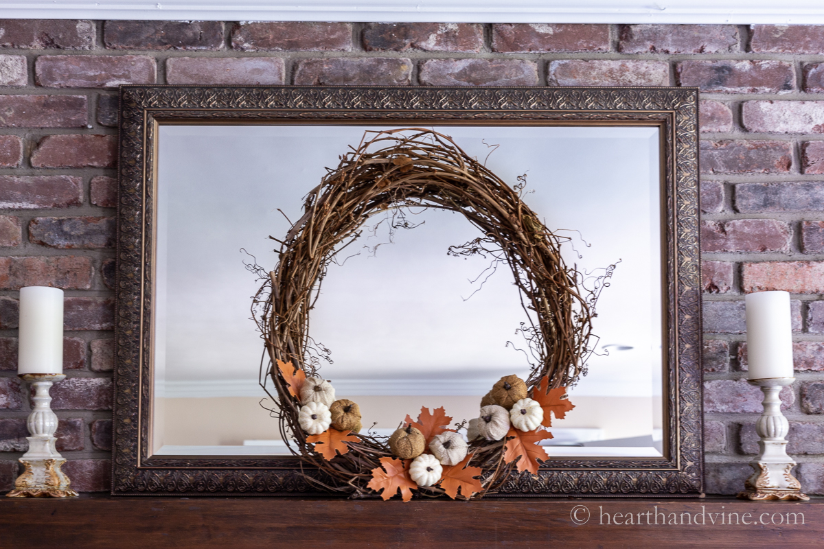 Dollar store fall wreath with a grapevine base and dollar store pumpkins and oak leaves.
