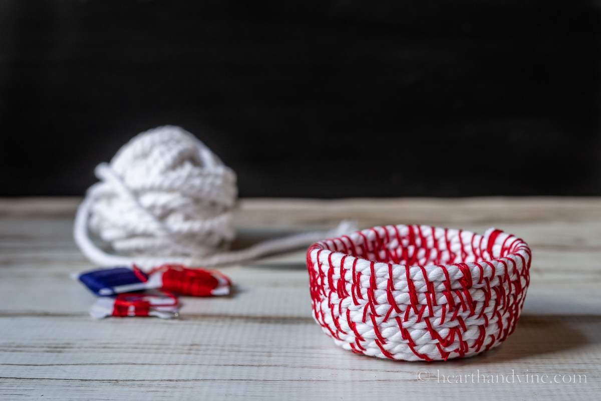 Ball of white rope, a couple of cards of embroidery thread and a small coiled red and white rope basket.