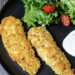Serving of Panko chicken on a plate with ranch dipping sauce and a salad.