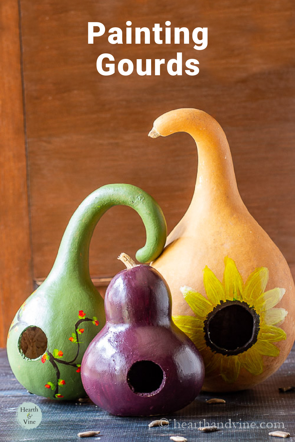 Three painted birdhouse gourds in green, yellow and deep purple colors.