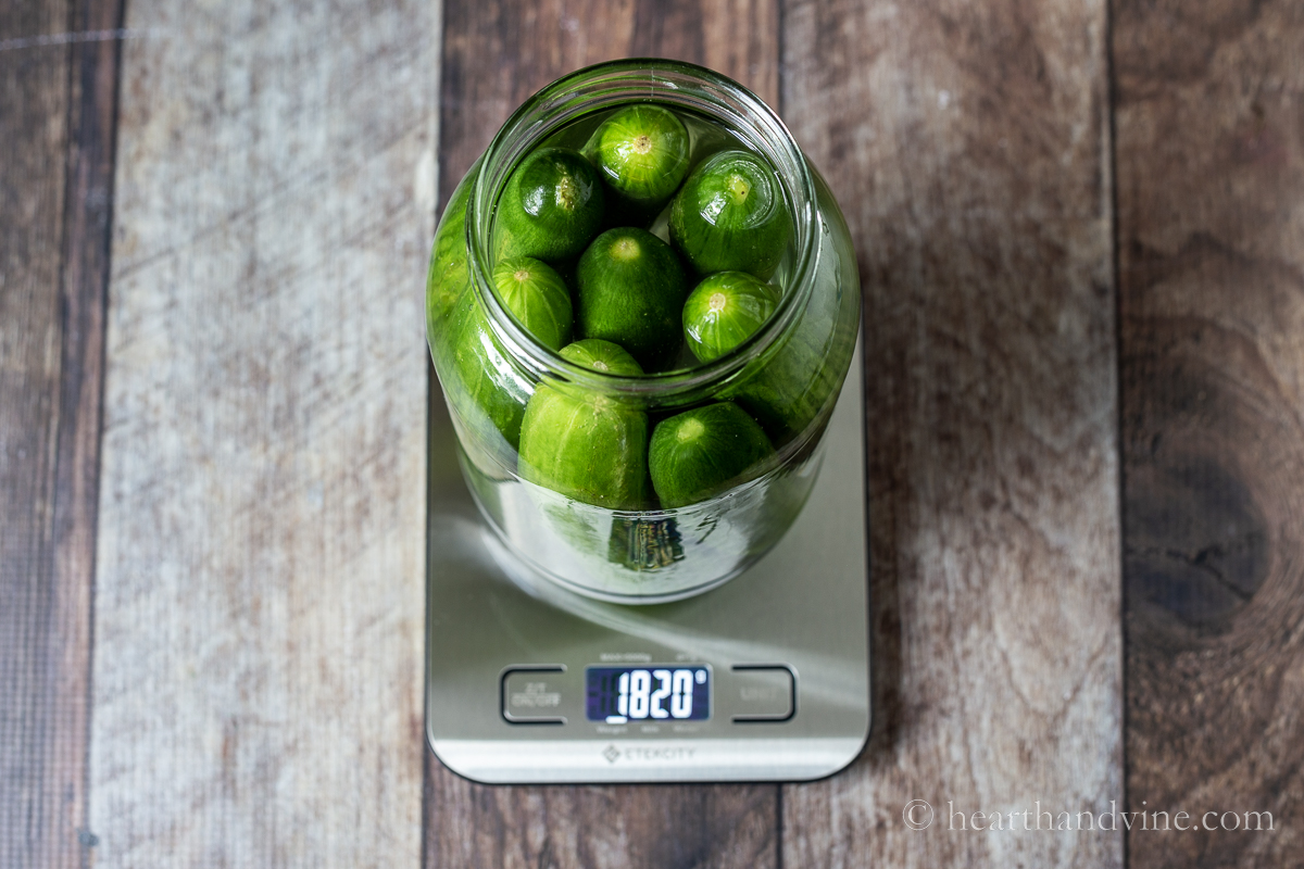 Cucumbers and water in a jar on a kitchen scale.