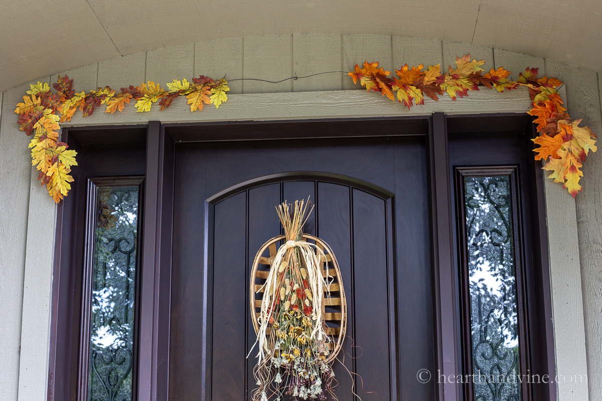 DIY faux fall leave garlands on top of a door frame. A fall swag on the door.