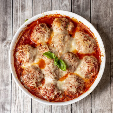 Round baking pan filled with meatballs, marinara sauce and cheese.