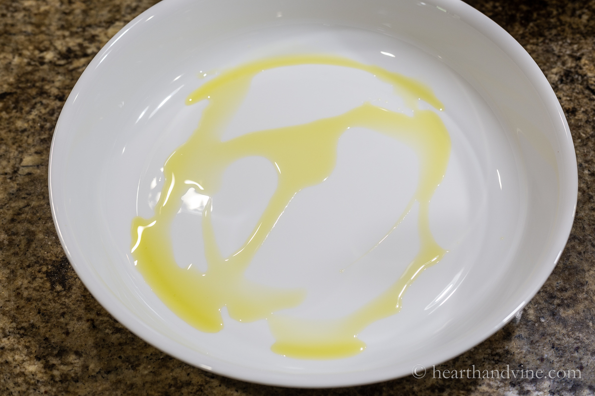 Round white baking pan with olive oil drizzled.