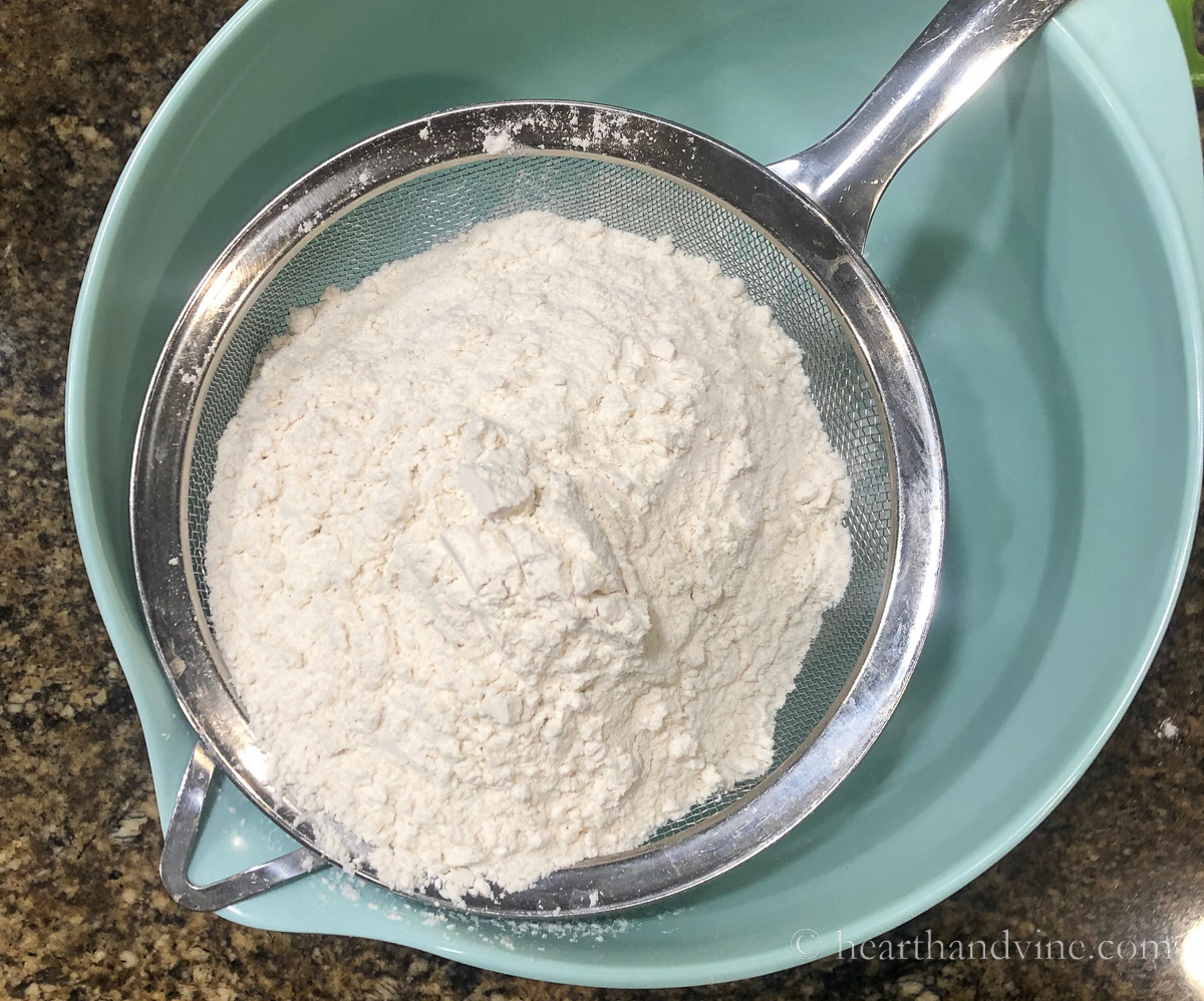 Flour in a sifter over a mixing bowl.