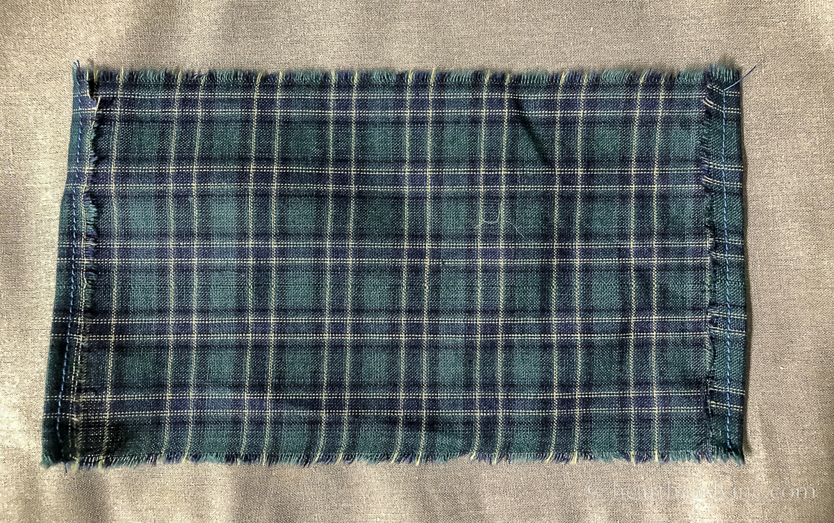 A piece of blue and green fabric with the sides folded and top stitched.