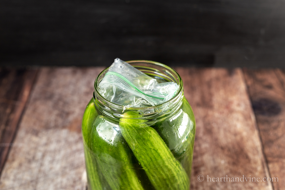 Cucumbers in brine in a jar with a water baggie on top.