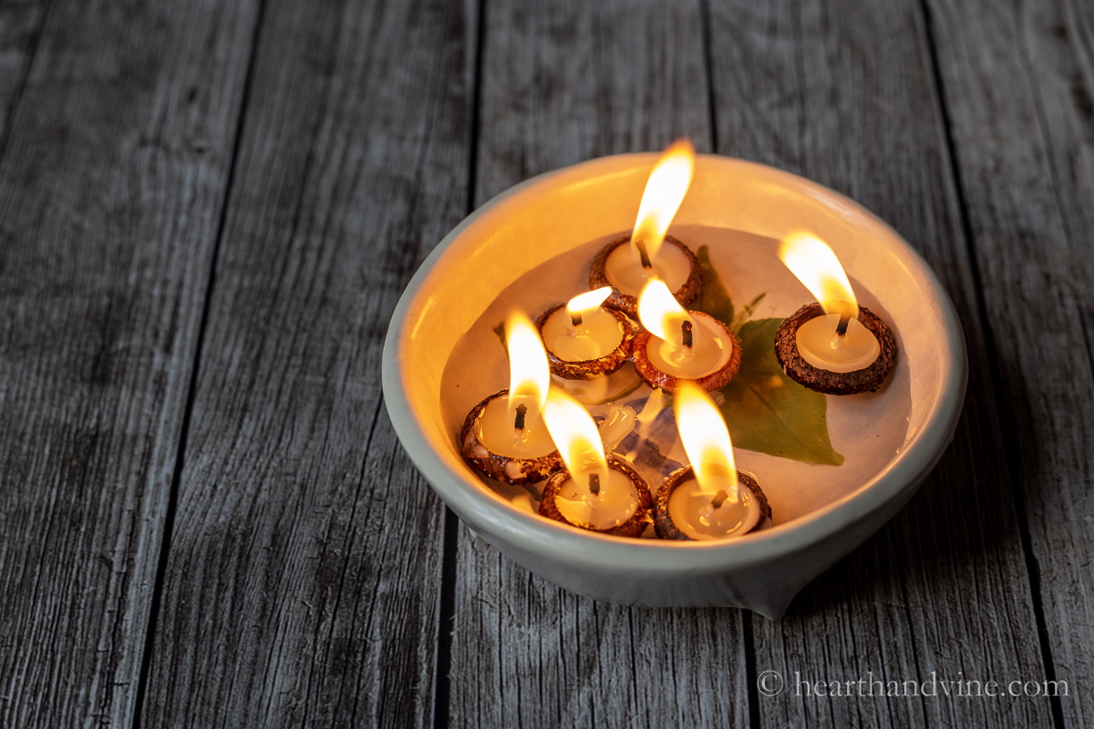 Acorn cap candles floating in water with large flames.