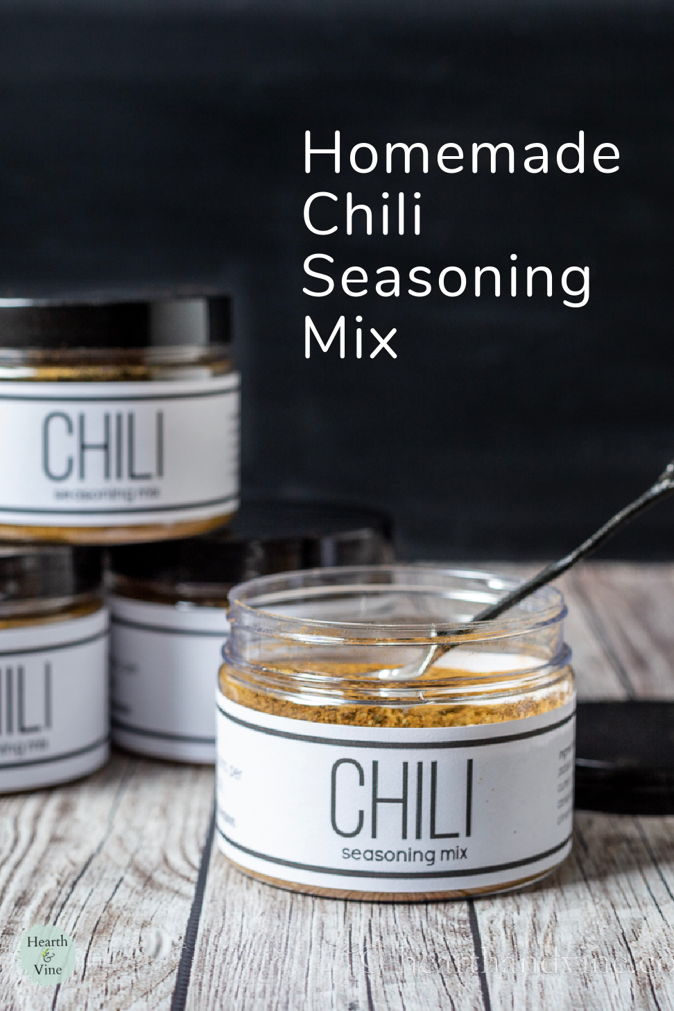 Chili seasoning mix jar with lid off and a small twig spoon in side.