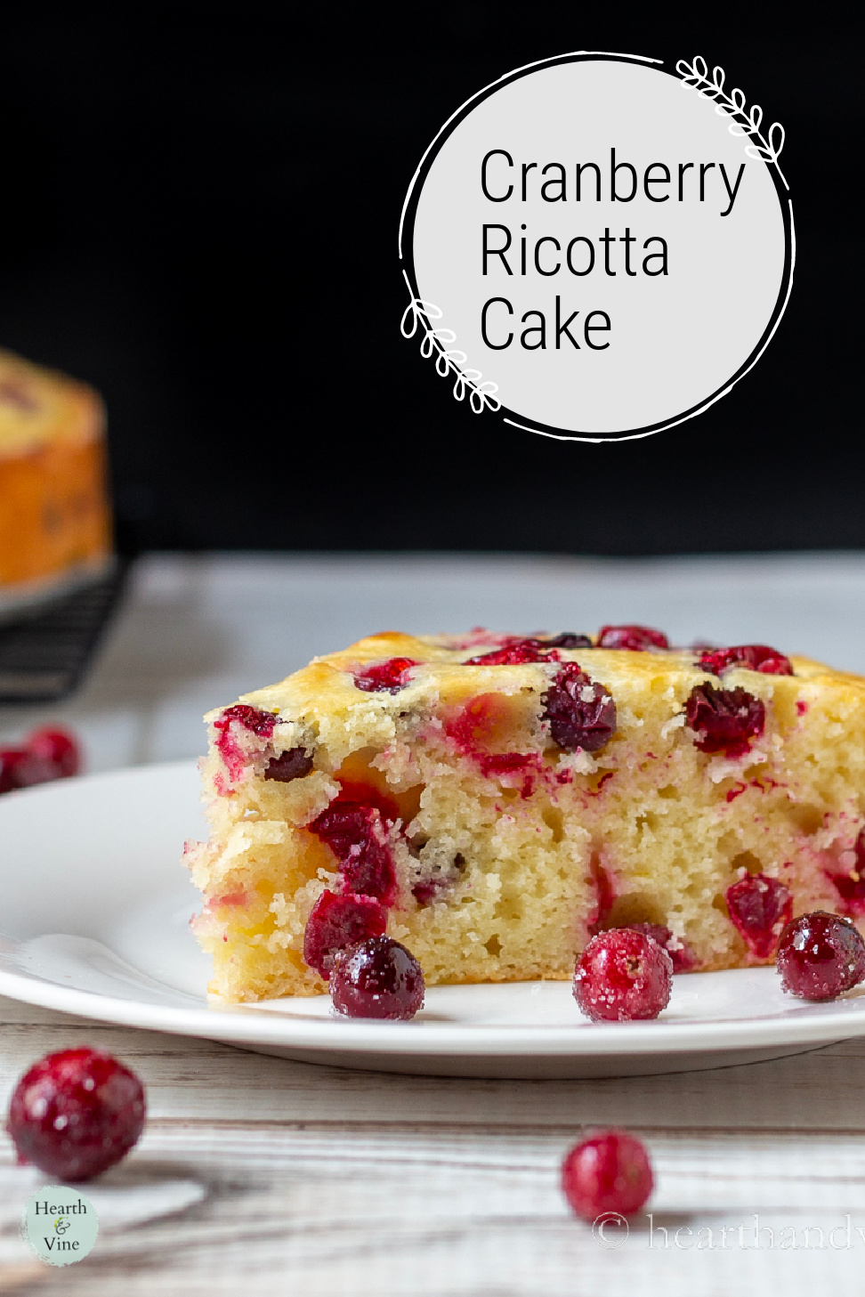 Slice of cranberry cake with sugared cranberries scattered around.