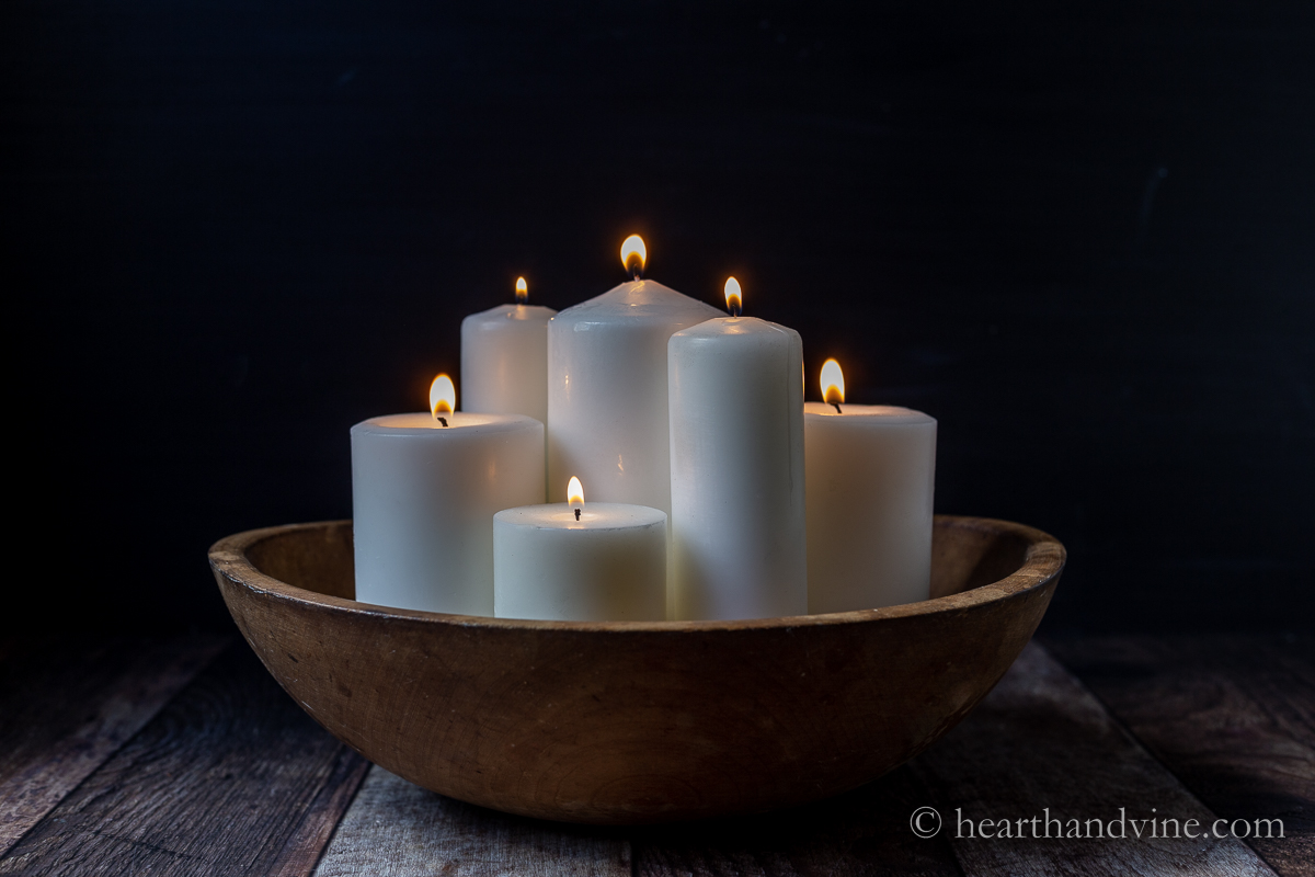 Dough bowl with white lit candles.
