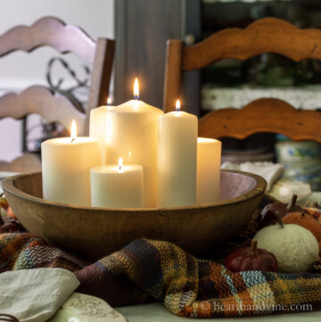 Wooden dough bowl centerpiece with pillar candles.