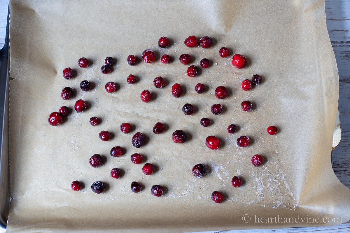 Cranberries in a pot on the stove in sugar syrup. A second image with the same cranberries rolled in superfine sugar and set on parchment to dry.