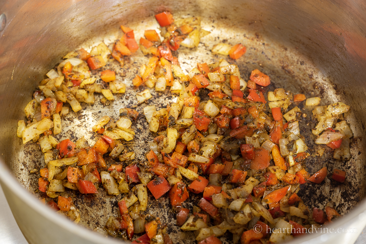 Onion and peppers with spices in a large pot.