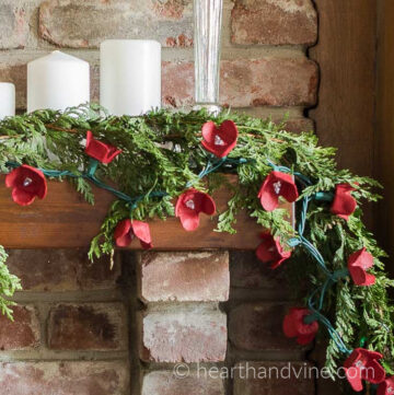 Egg carton red flowers on string of lights on a mantel garland.