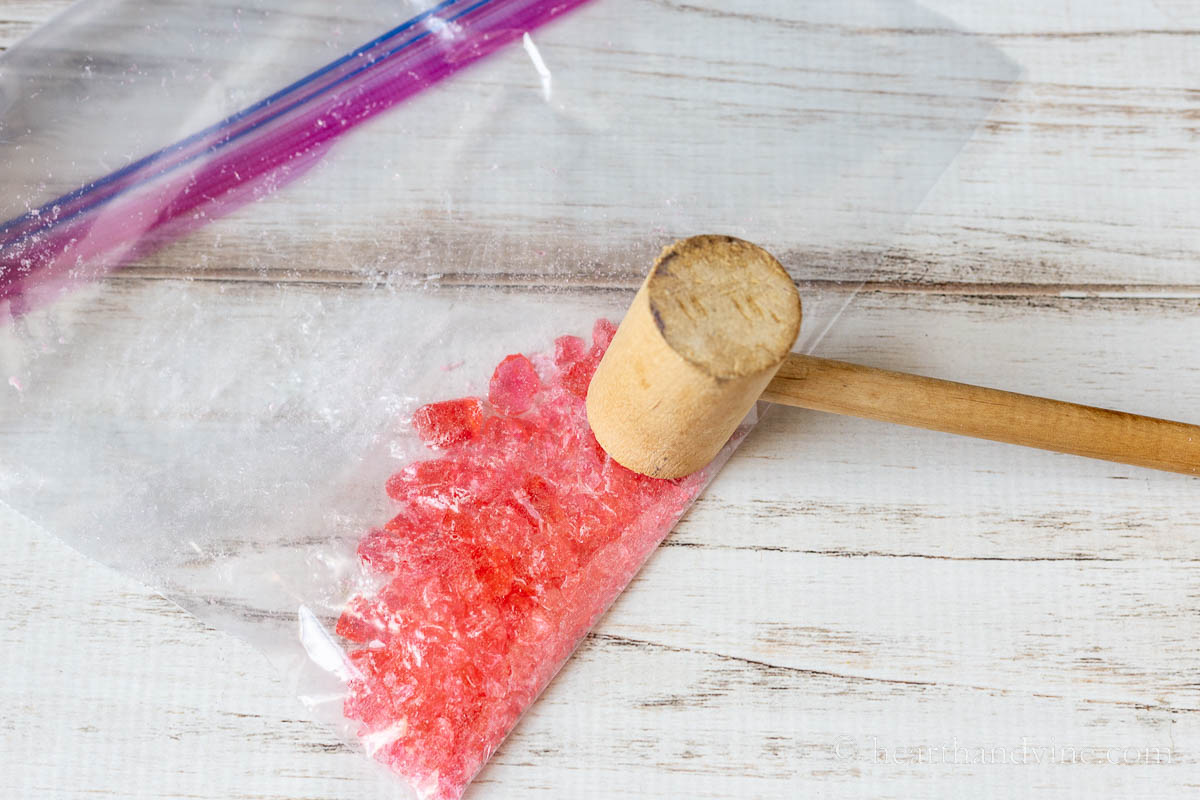 Crushed hard candy in a plastic bag with a wooden mallet.