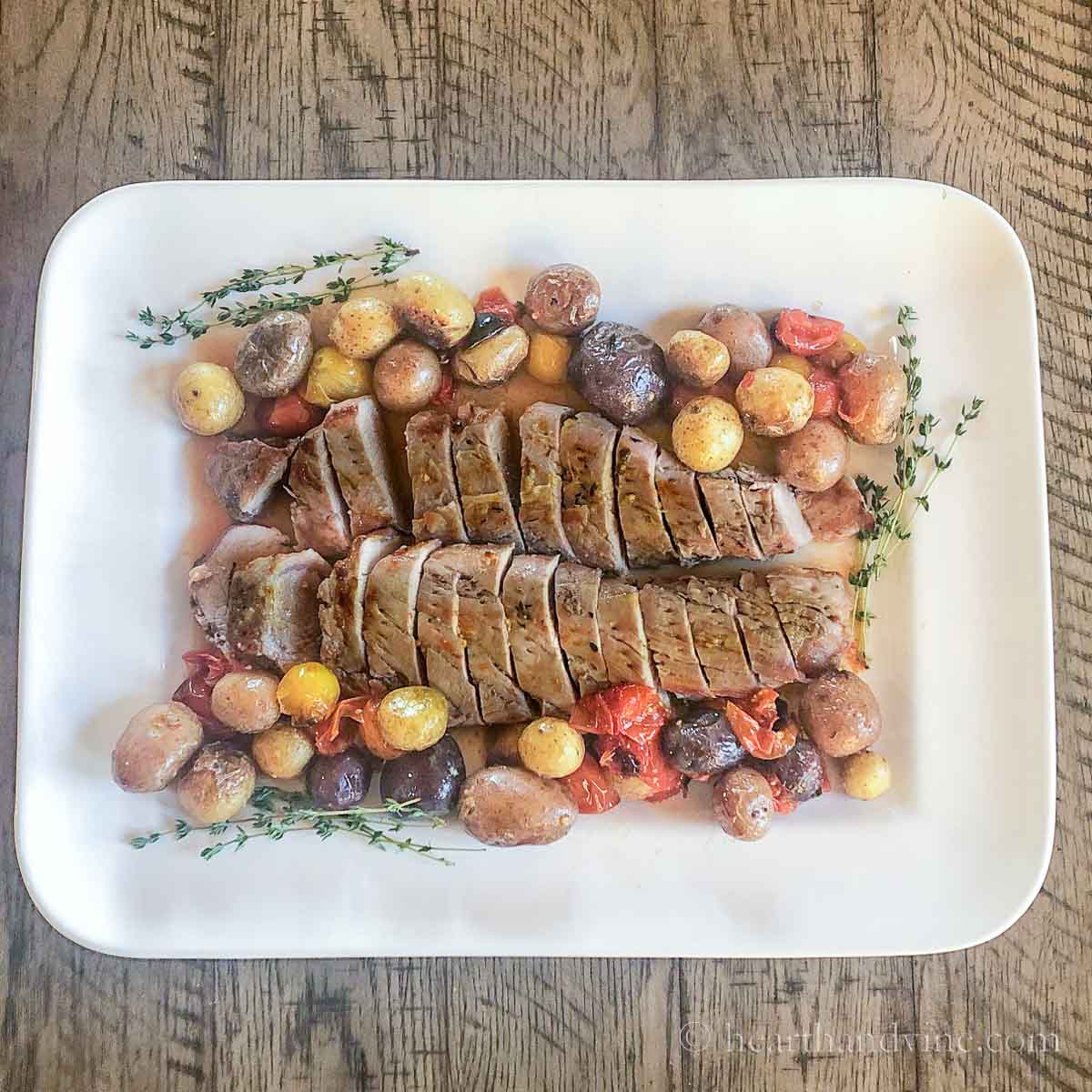Platter of pork tenderloin dinner with potatoes and tomatoes on a serving platter.