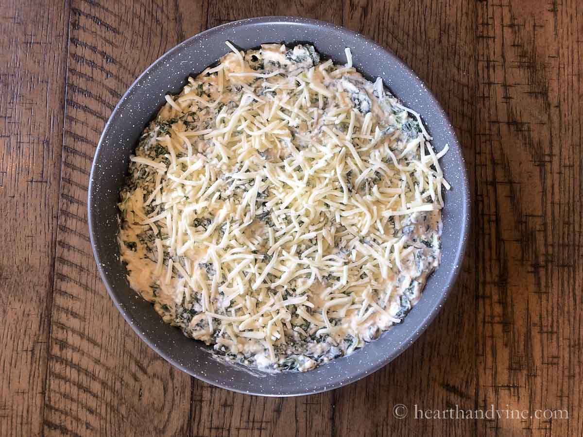 Spinach dip in a baking pan before baking in the oven.