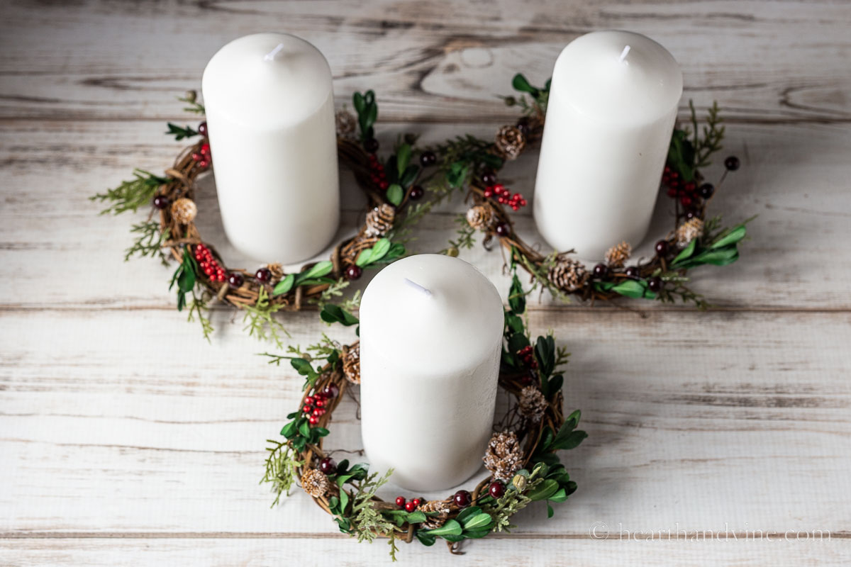 Three DIY candle rings with white pillar candles set inside.