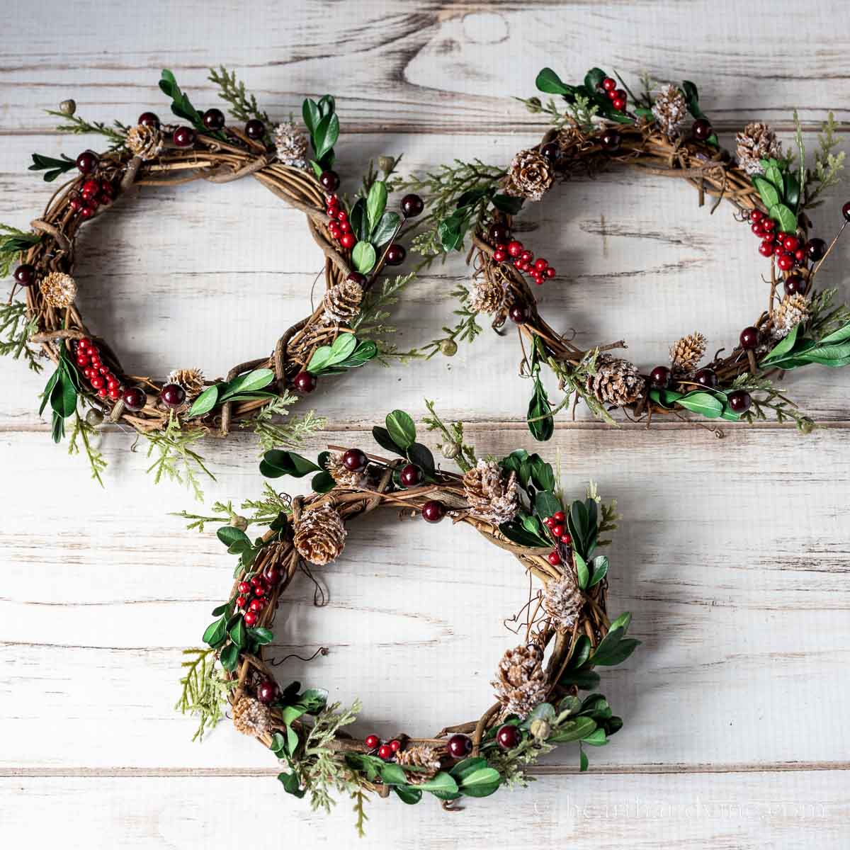 Three candle rings on grapevine bases with faux greenery.