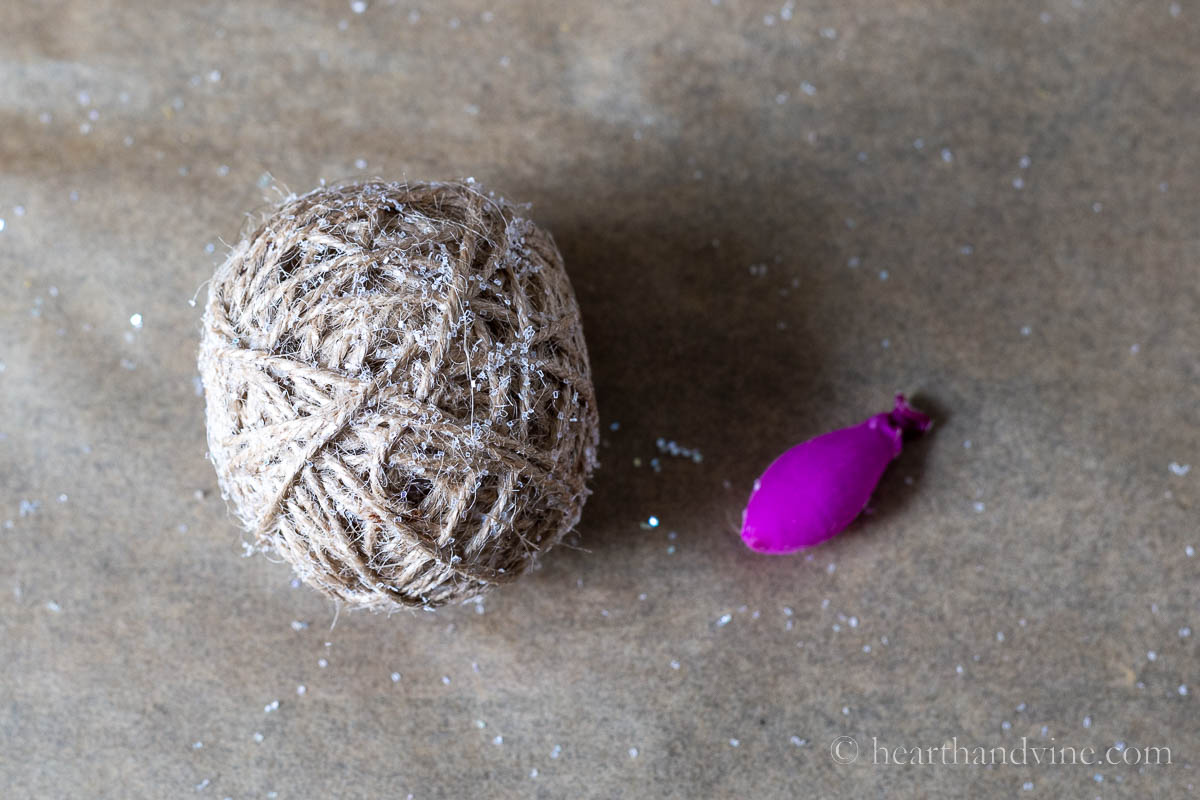 Twine ball ornament next to a popped balloon.