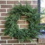 Fresh evergreen wreath on brick wall.