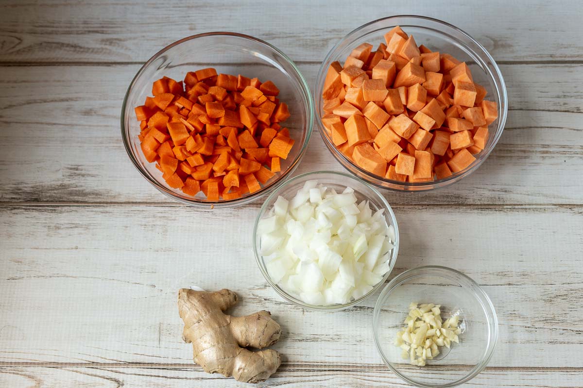 Bowls of diced sweet potatoes, carrots, onions and garlic and some ginger root.