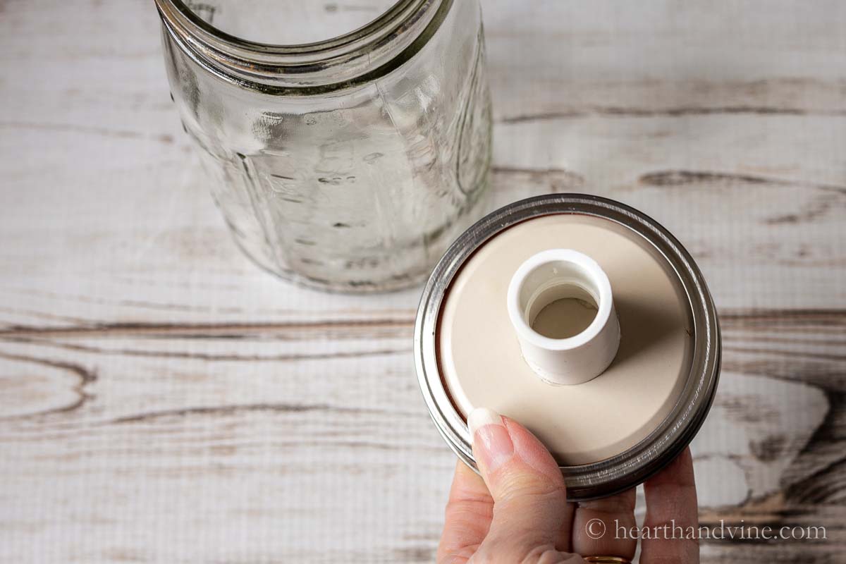 A plastic coupling glued to the underside of a mason jar lid.