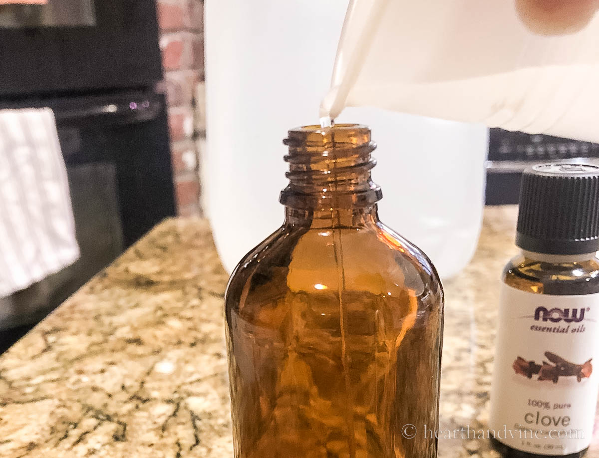 A plastic cup pouring liquid into an amber glass bottle.